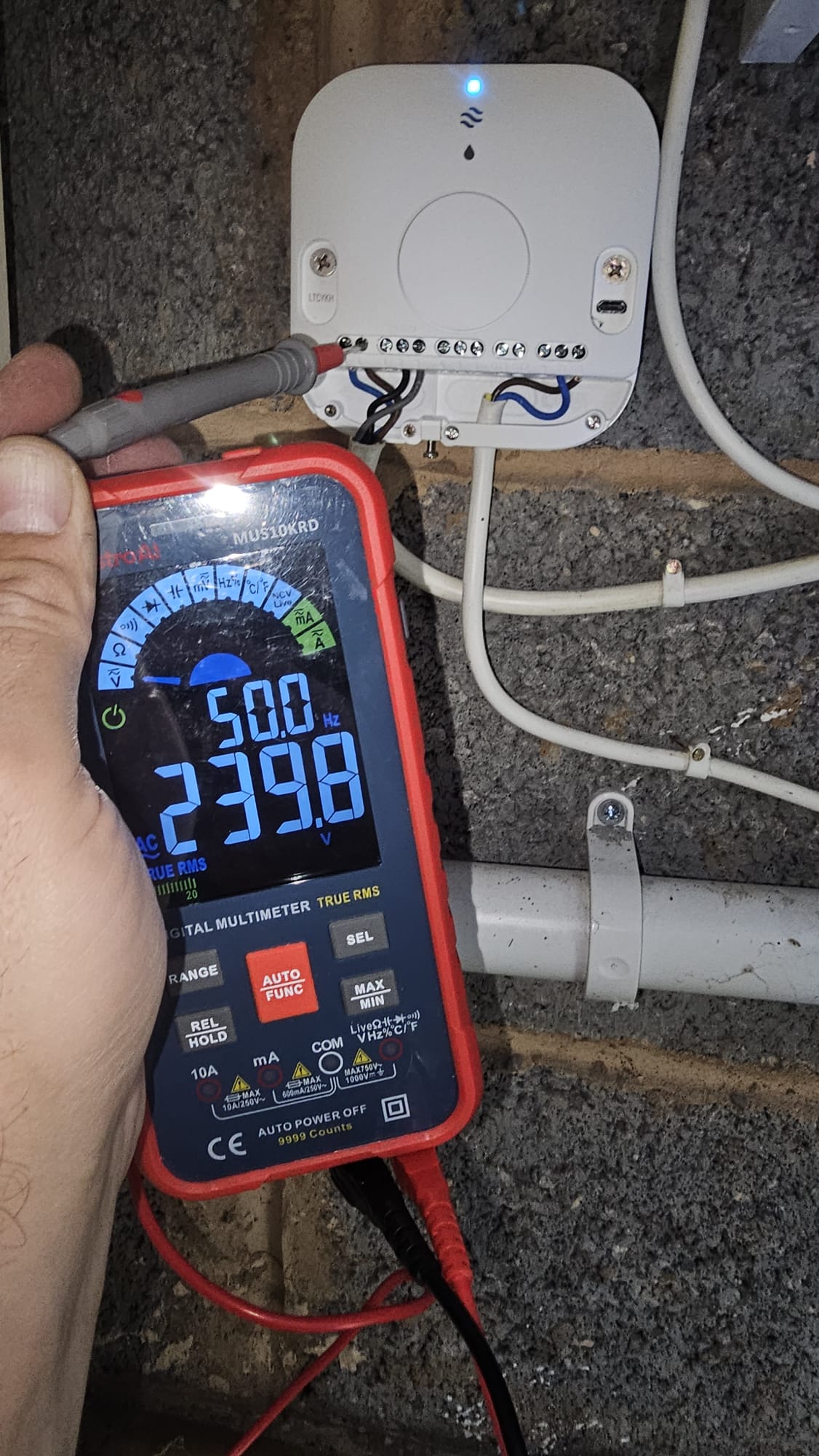 Smart thermostat wiring centre being tested with an electrical multimeter.