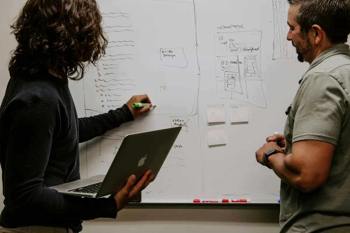 A man and a woman planning a strategy on a whiteboard