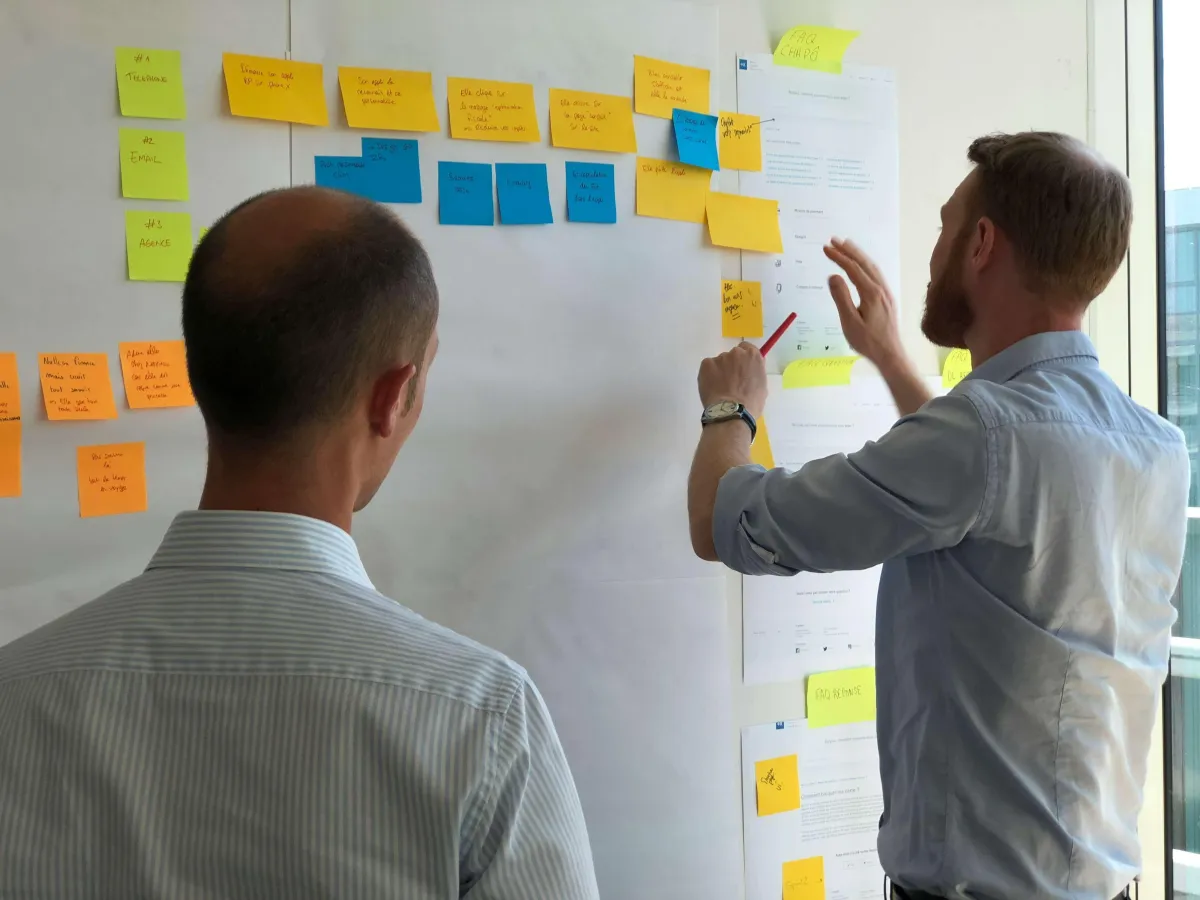 Two men looking at post it notes bringing together a strategy