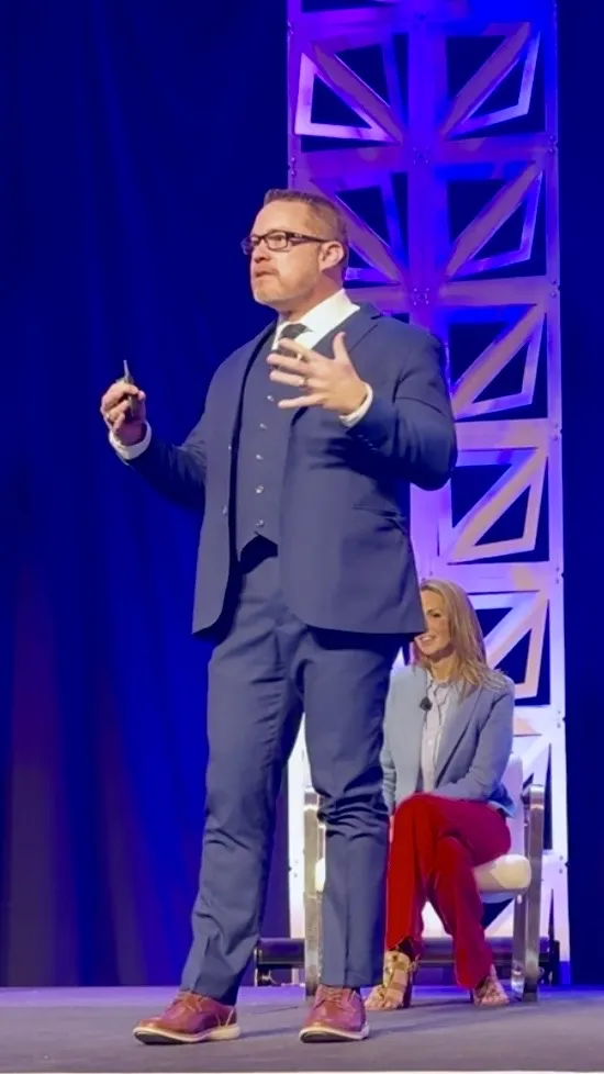 James Morgan delivering a healthcare keynote to a professional audience at a live event