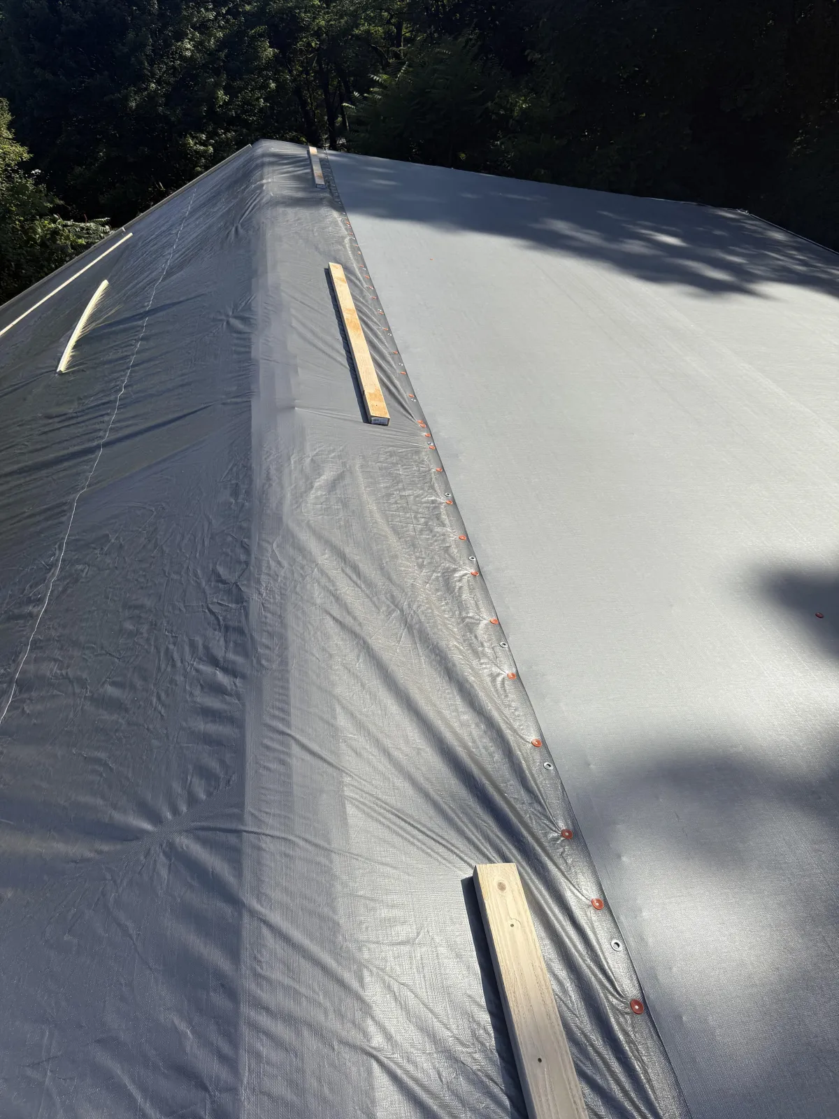 Storm-damaged residential roof covered with tarp after severe wind and rain in Western Pennsylvania