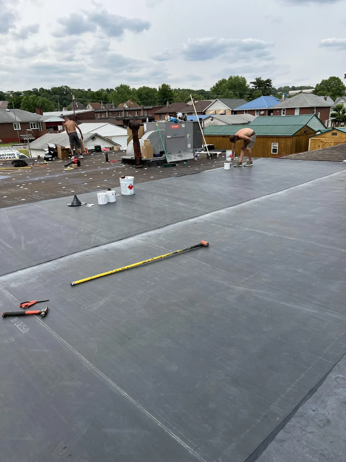 Commercial flat roof replacement showing rubber membrane being laid out and secured during installation in Brackenridge PA