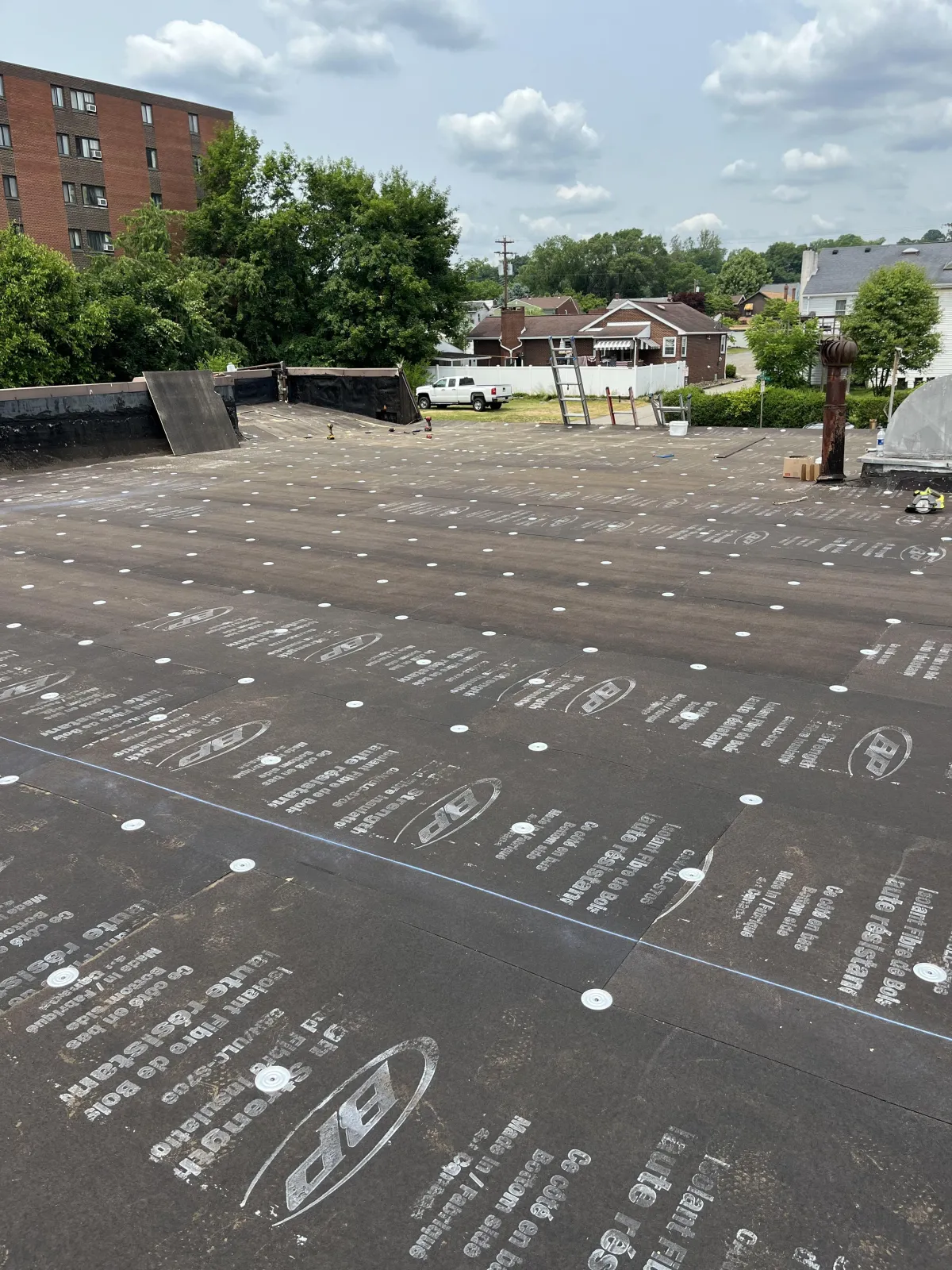 Commercial flat roof insulation board installation secured with screws and plates in Brackenridge PA