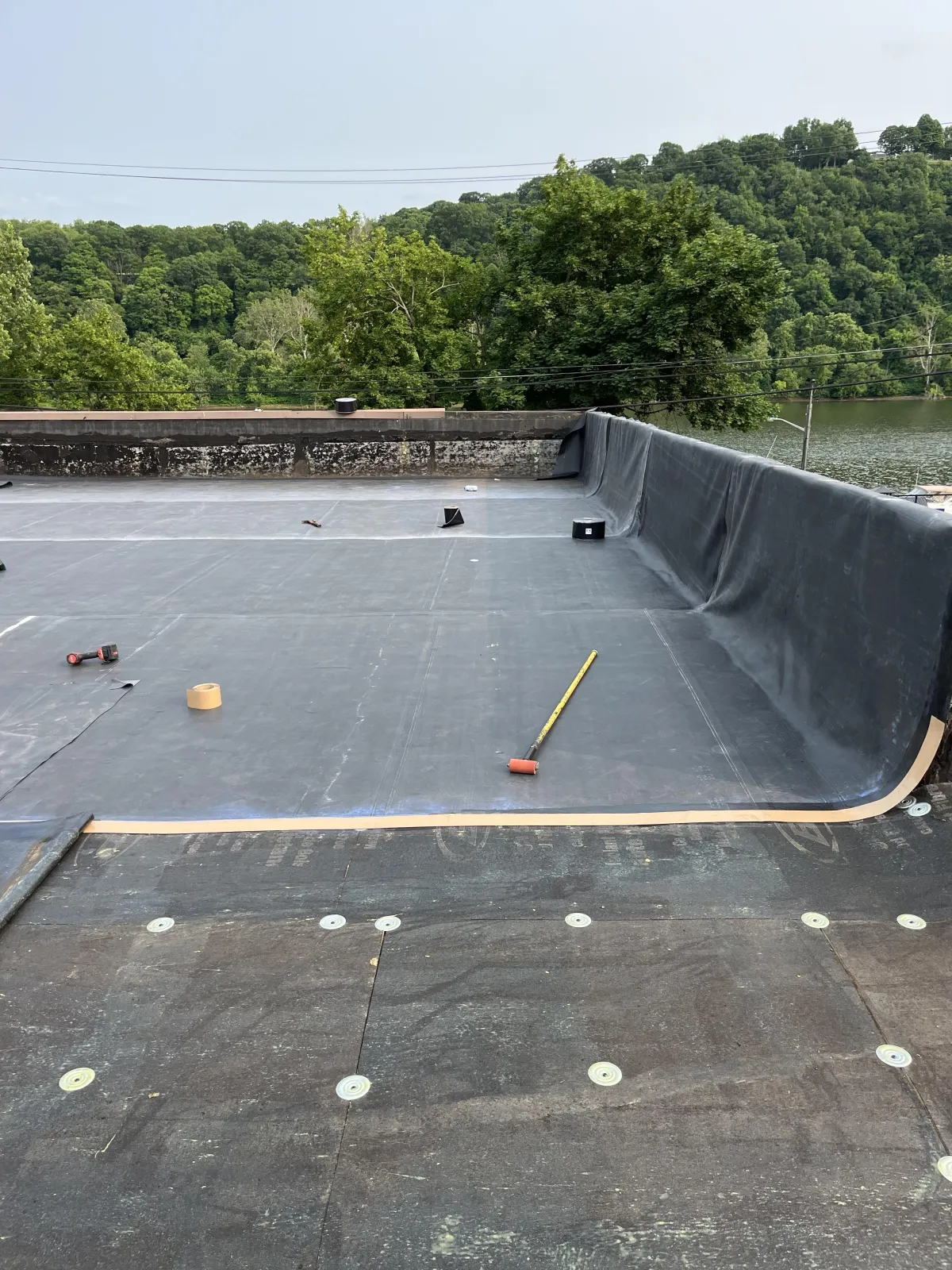 Rubber roofing membrane being installed on a commercial flat roof during replacement project in Brackenridge PA