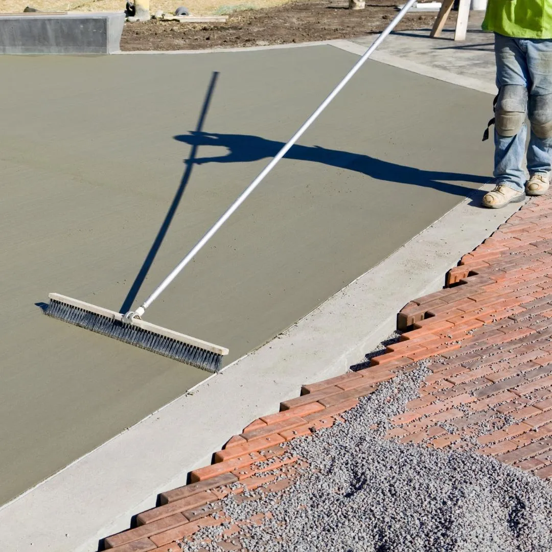 Concrete contractor brushing newly poured concrete cement