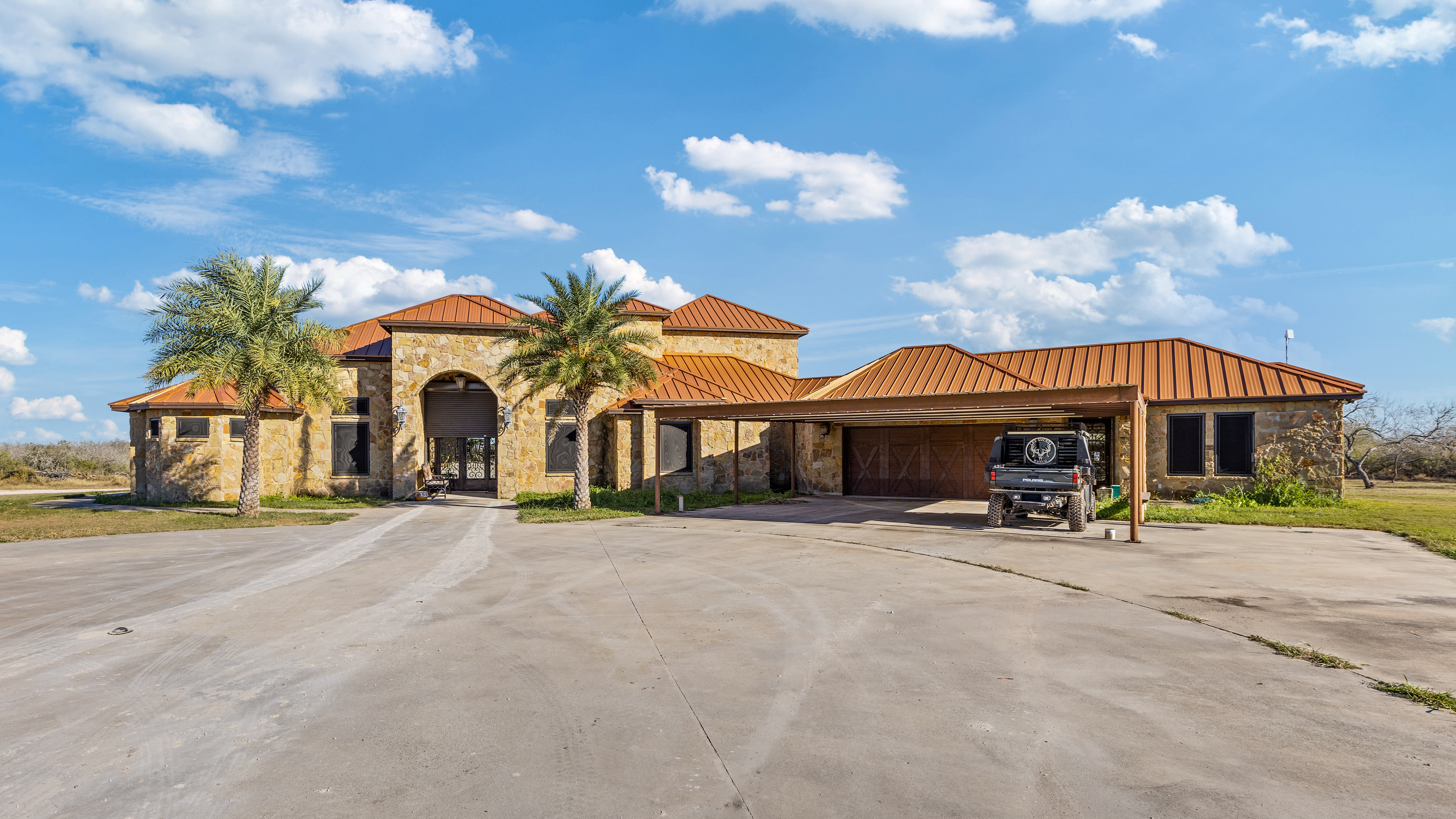 Barndominium-style custom home exterior with metal siding, covered front porch, black-framed windows, and wood ceiling detail.