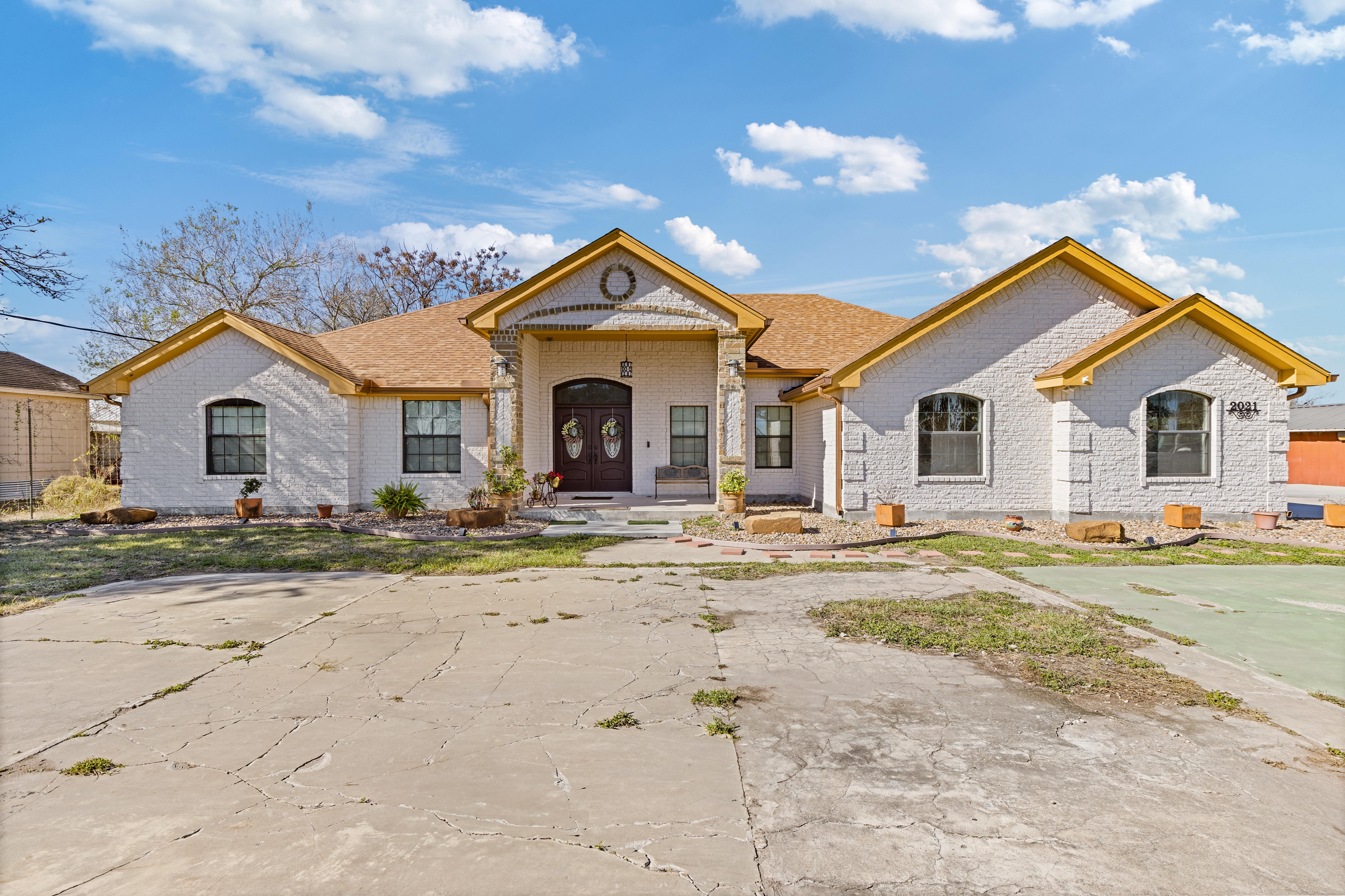 Brick modern farmhouse exterior with black metal roof, large windows, and covered front entry by South Texas Builders.