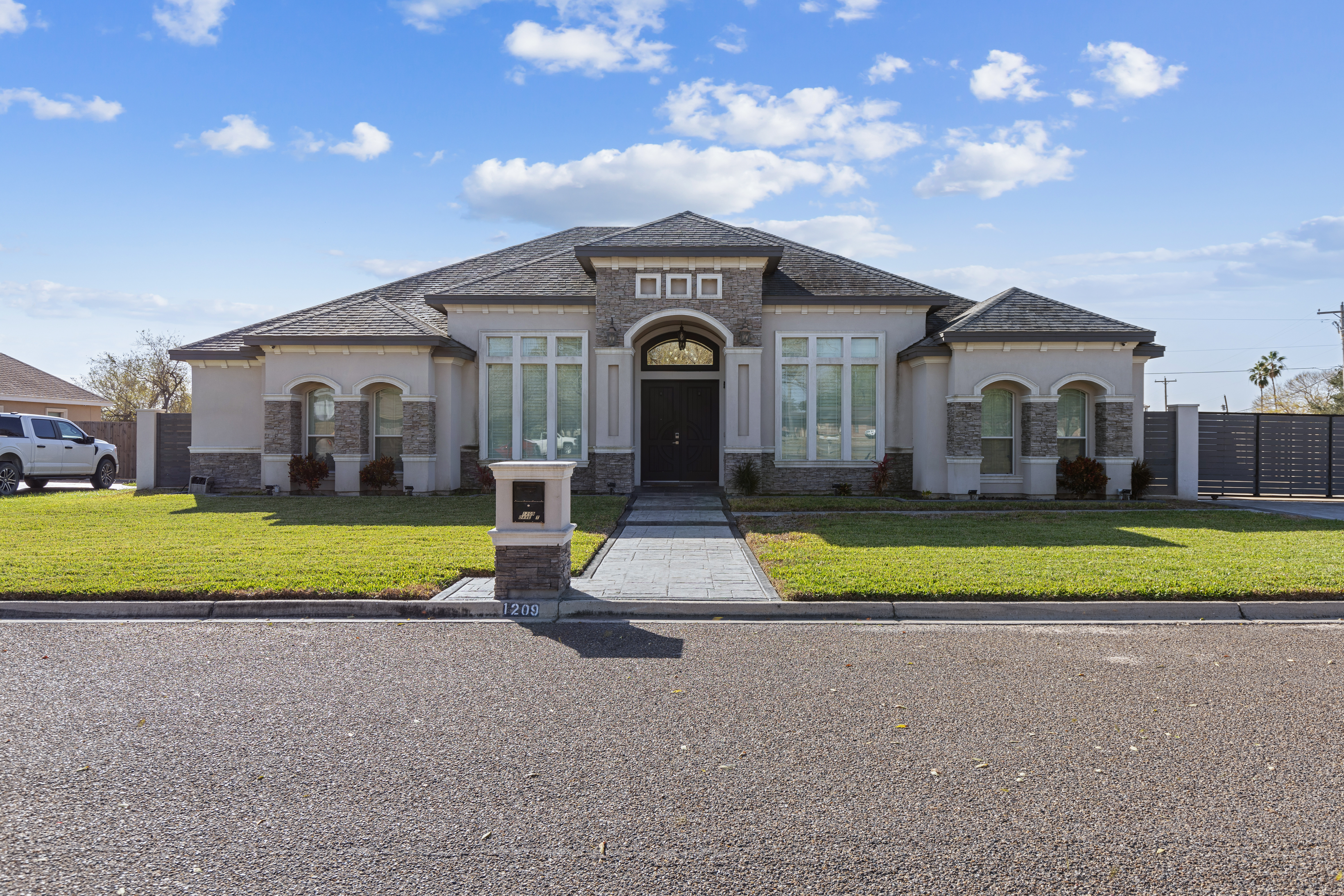 Luxury South Texas custom home exterior with stucco, stone accents, arched windows, and grand front entry.