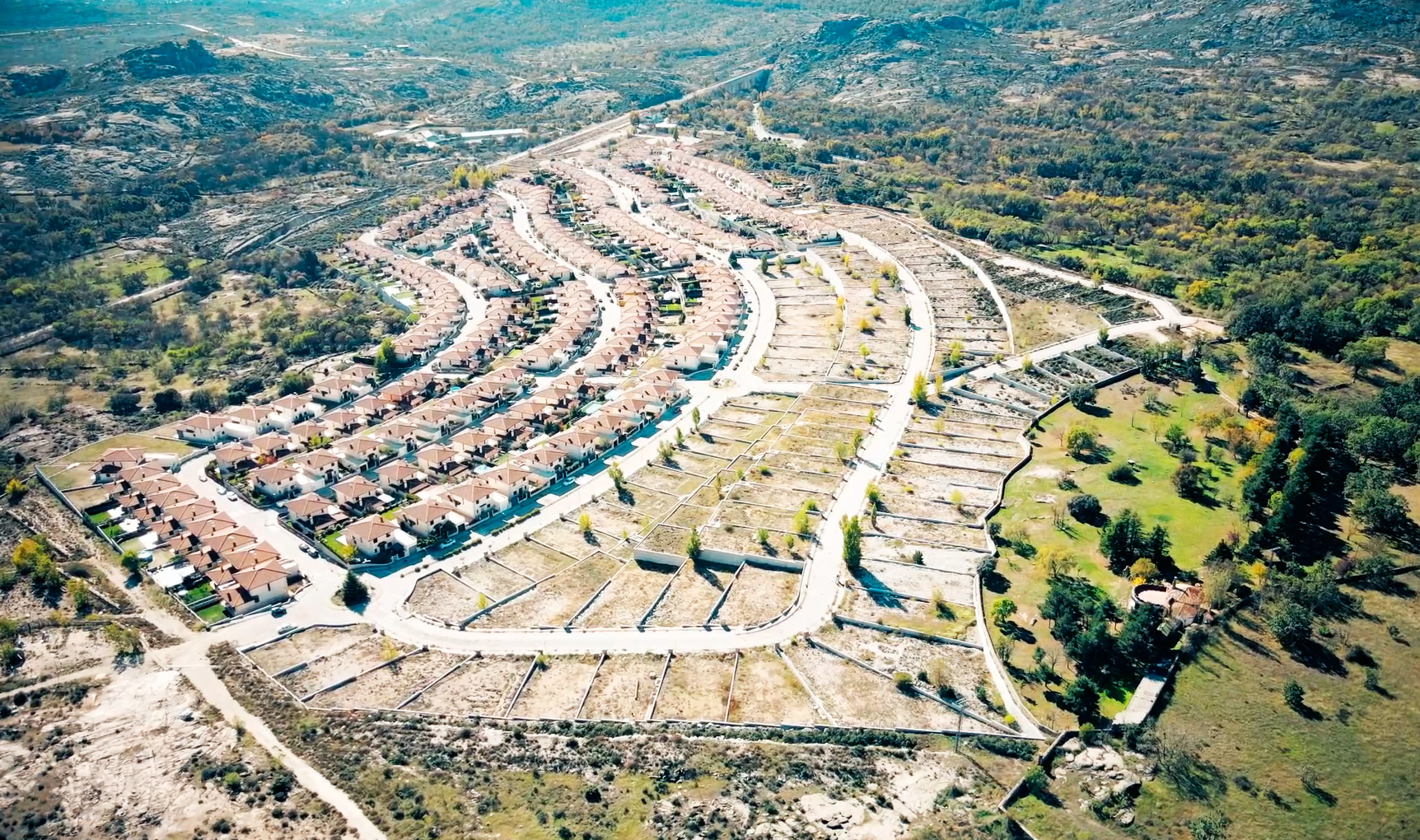 Terraza exterior con zona de comedor, césped cuidado, plantas autóctonas y vistas despejadas a la montaña, ideal para reuniones familiares y momentos de relax al aire libre.