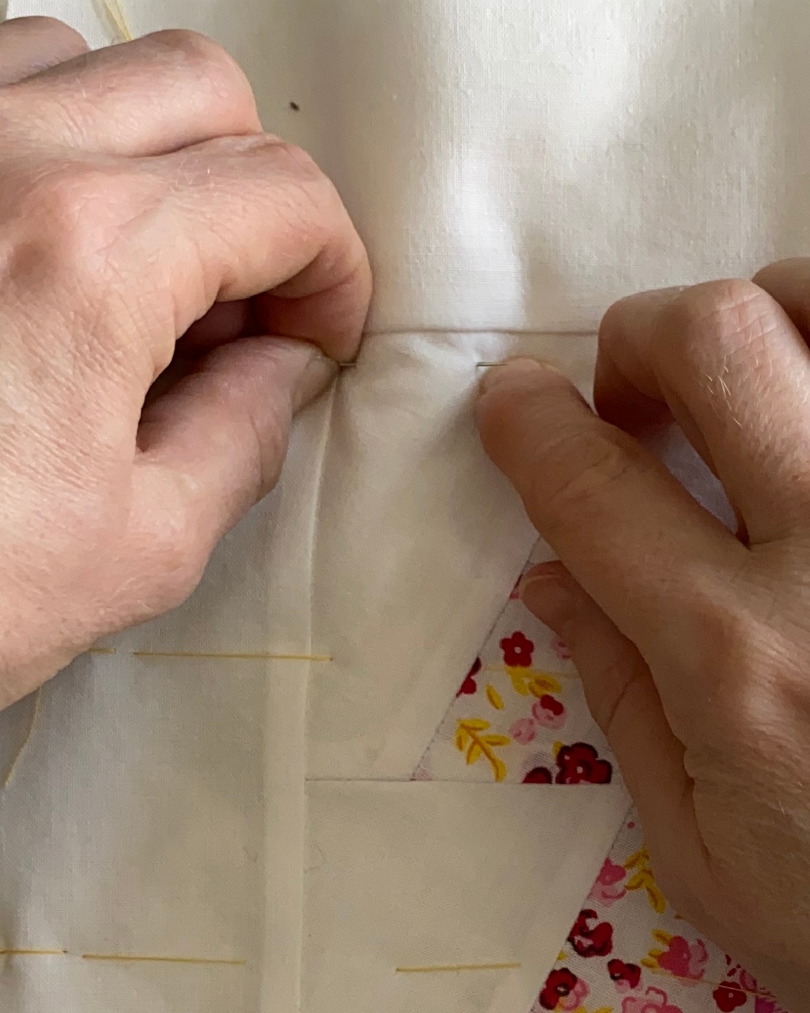 Nærbilde av to hender som tråkler en quilt