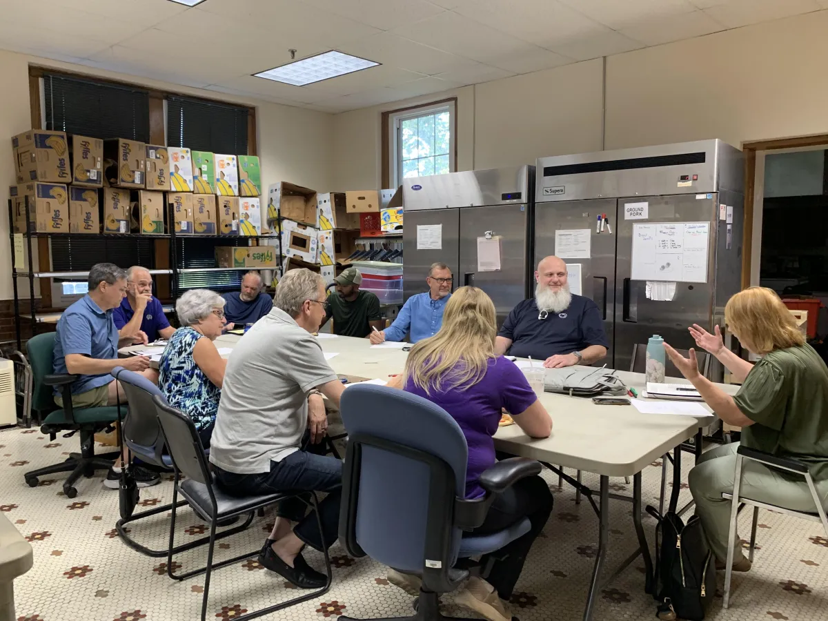 Board members sitting around a table in the pantry for a meeting.