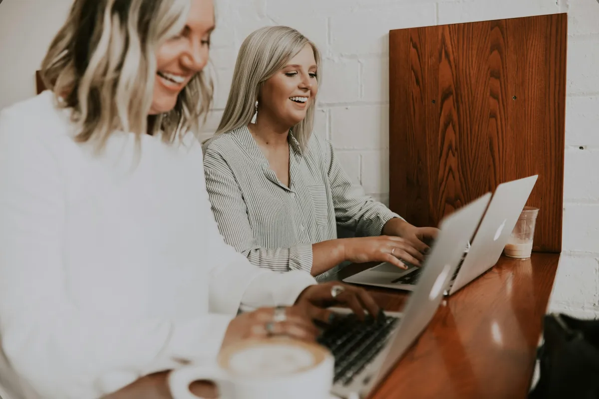 Small business owner working confidently at a desk in a modern office, using a laptop with IT monitoring dashboard in the background, representing proactive IT support for businesses.