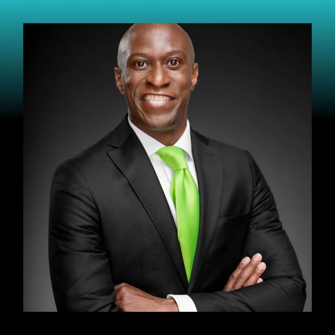 Headshot of a smiling man in a suit against a blue background