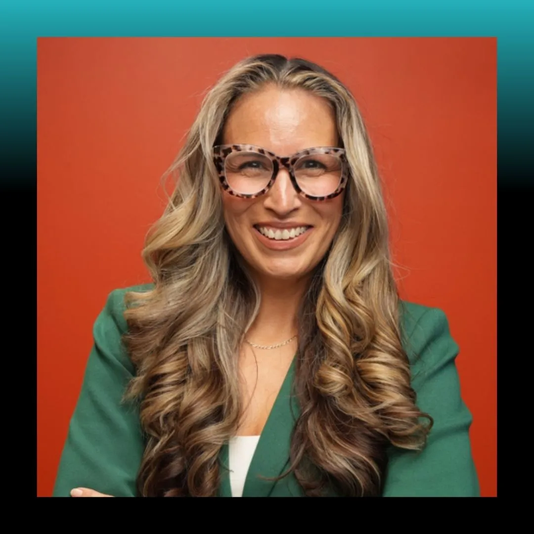 Headshot of a smiling woman in glasses against a blue background