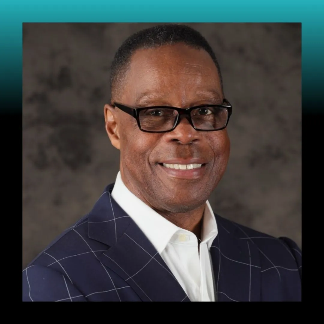 Headshot of a smiling man in glasses against a blue background