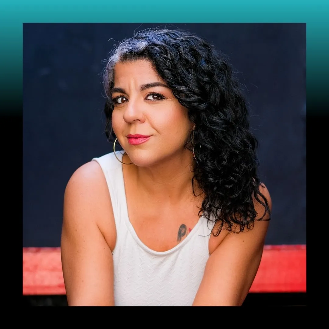 Headshot of a smiling woman in a dark top against a blue background