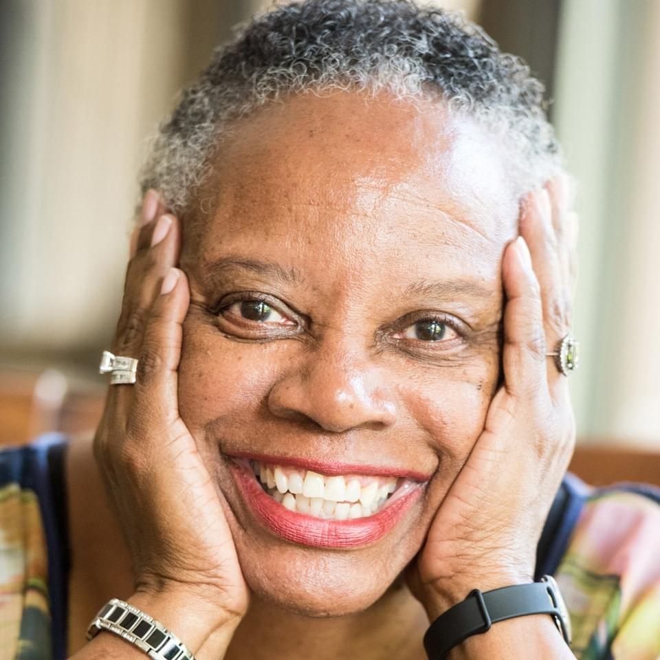 Senior black woman smiling and holding head in hands
