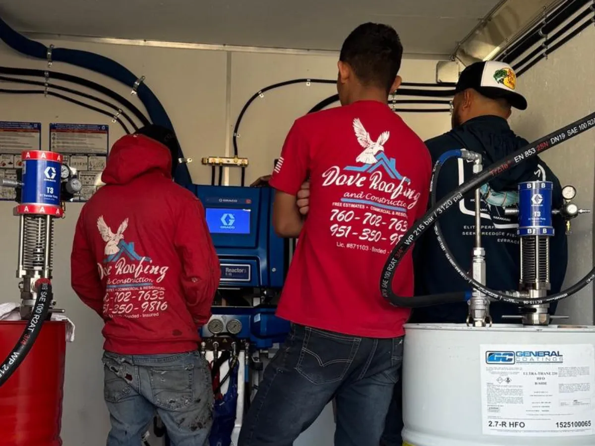 Three Dove Roofing technicians in red branded uniforms  operating professional spray foam roofing equipment