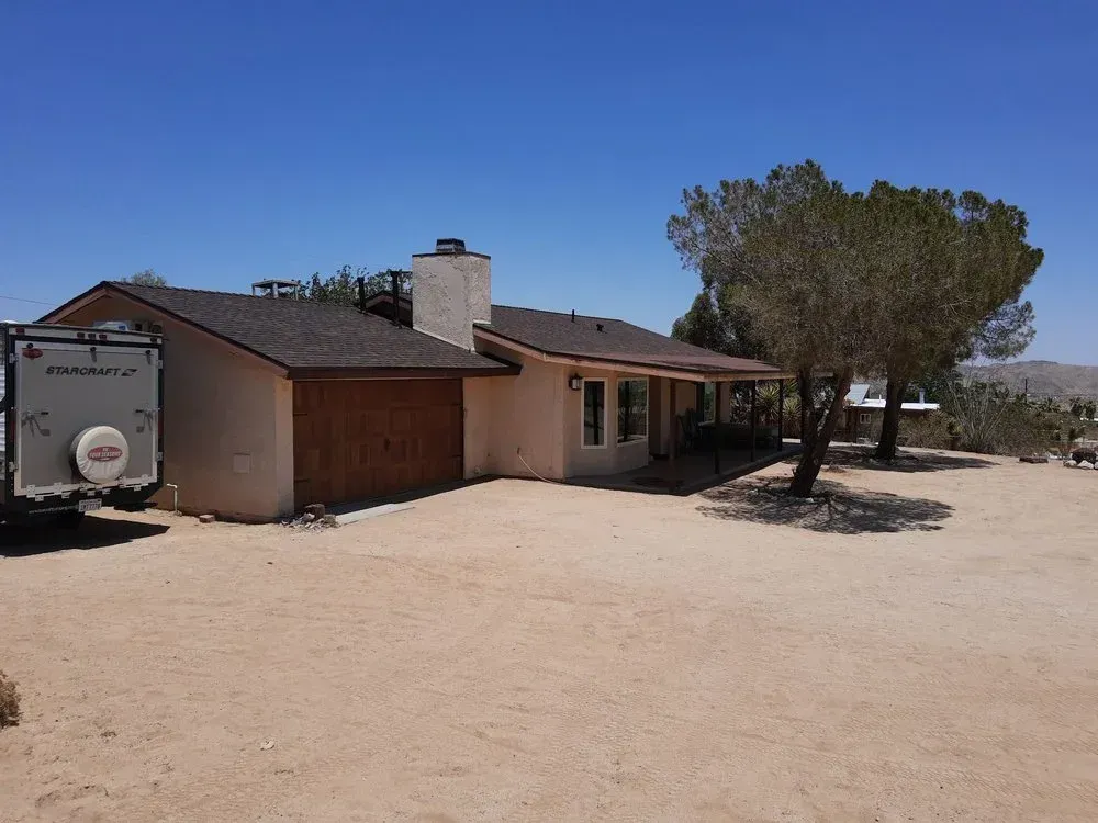 Single-story stucco ranch home with asphalt shingle roof in desert — roofing Yucca Valley CA