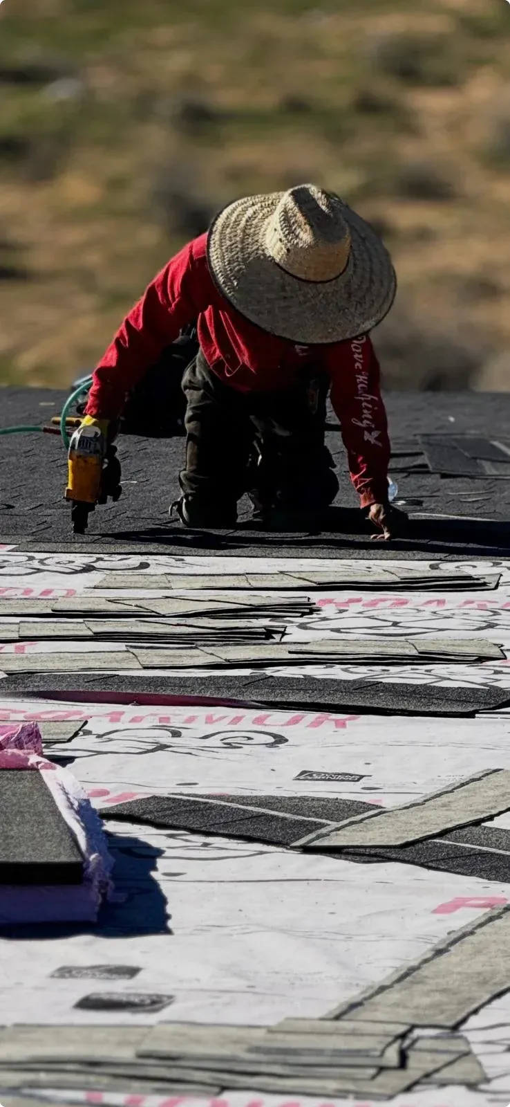 Roofers nailing dark asphalt shingles on residential roof during new installation — how long does it take to replace a roof