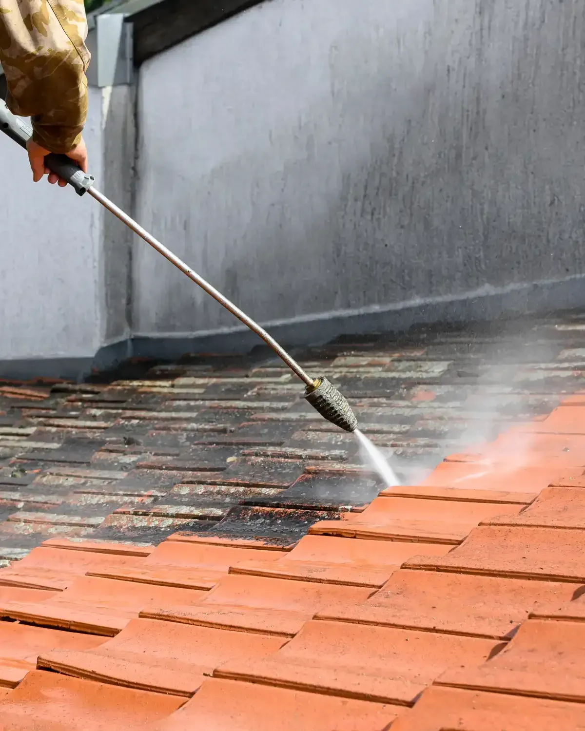 High-pressure wand blasting moss off red clay tile roof — roof inspection Palm Desert CA