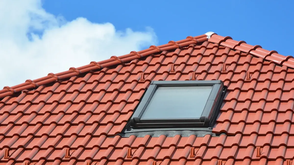 Black vented skylight on terracotta tile roof under blue sky — roofing services Palm Springs CA