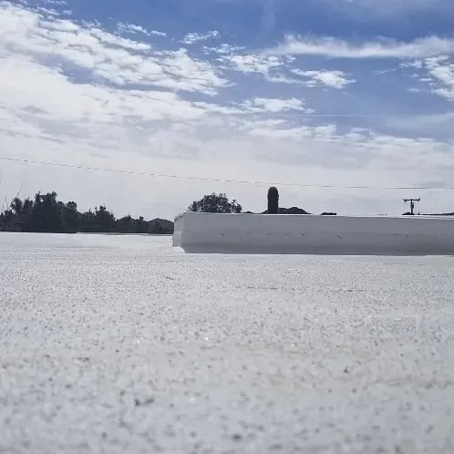 White silicone flat roof at low angle with parapet under desert sky — is roof coating worth it in Southern California