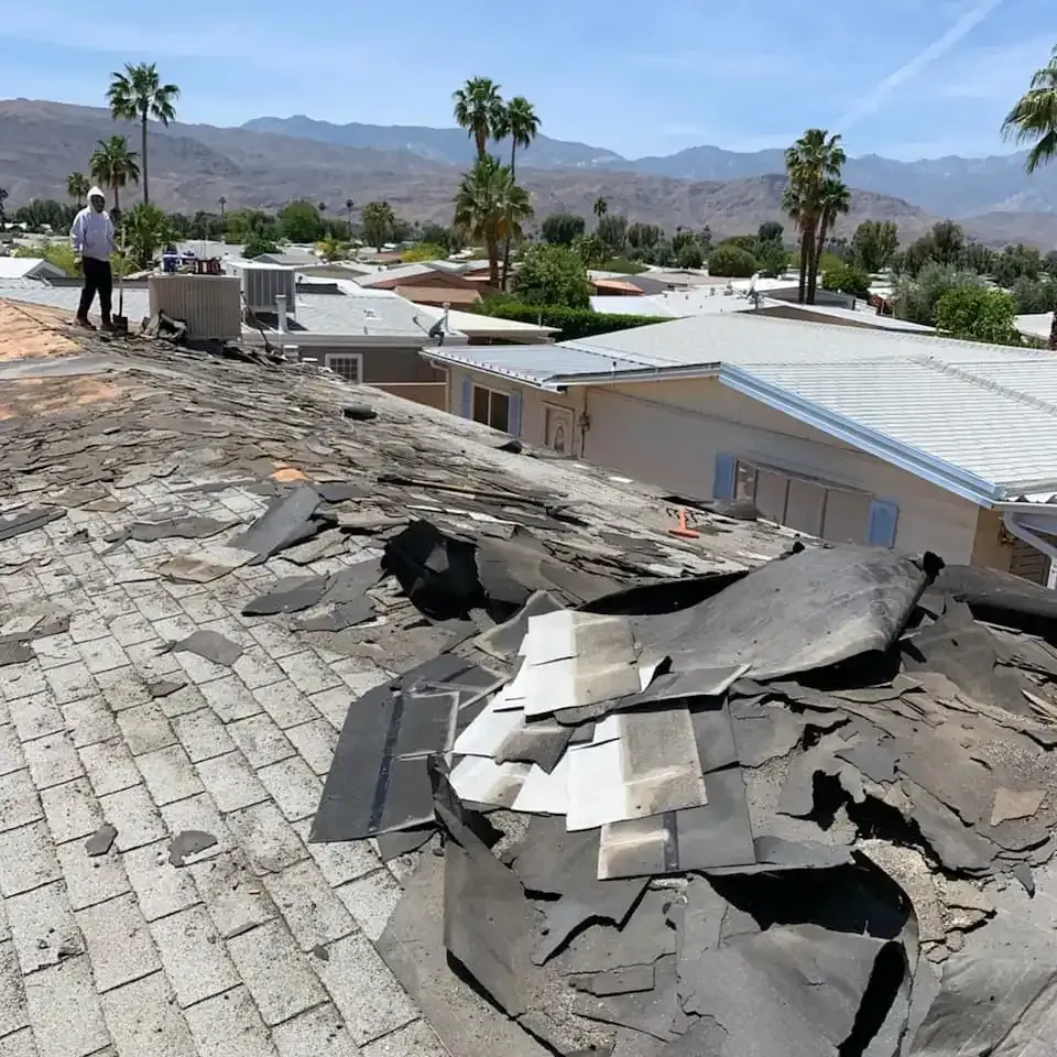 Severely storm damaged asphalt shingle roof with large  section blown off showing roof deck before Dove Roofing emergency repair