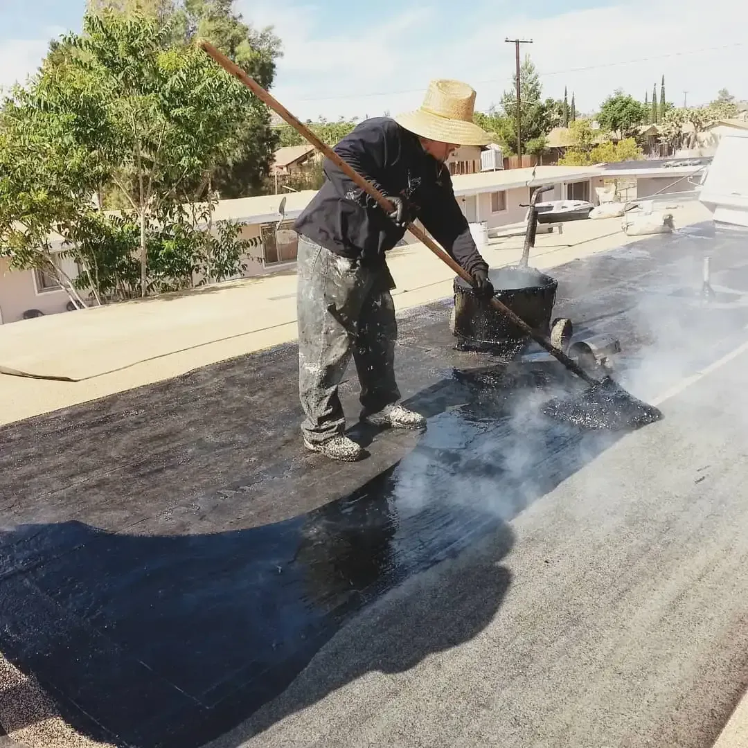 Dove Roofing technician applying hot mop modified  bitumen roofing system on flat residential roof in Southern California