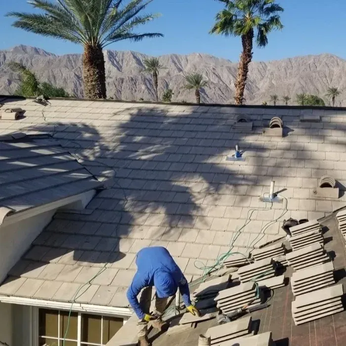 Dove Roofing installer working on tile roof installation  with palm trees and Coachella Valley mountains in background