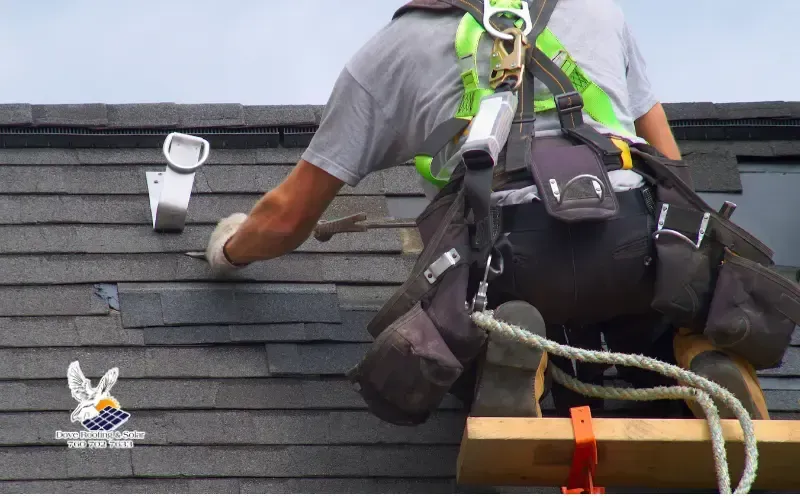 Roofer wearing a safety harness installing asphalt shingles, Dove Roofing & Solar watermark