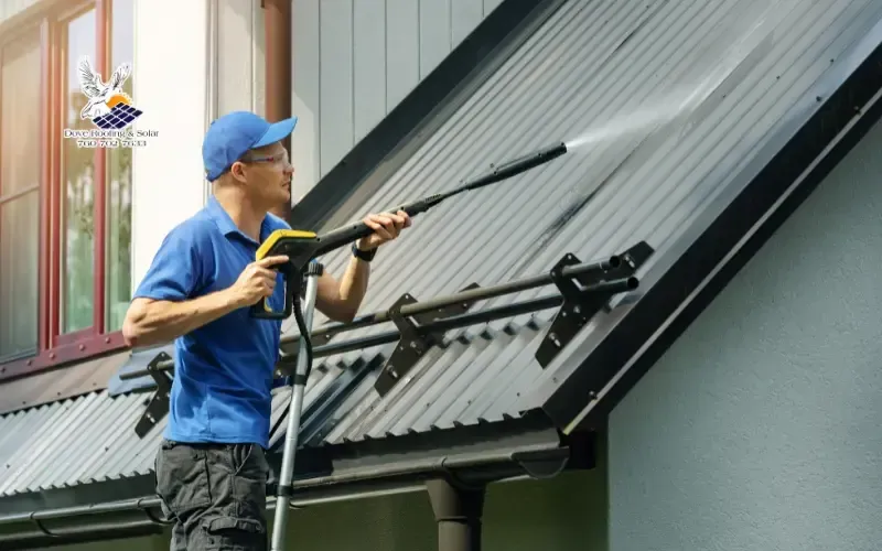 Roofing technician pressure washing a metal roof panel