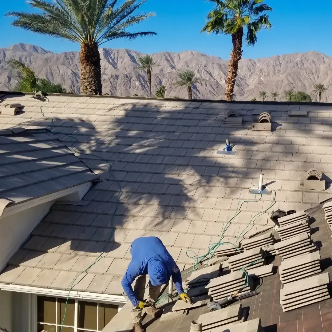Dove Roofing installer working on tile roof installation  with palm trees and Coachella Valley mountains in background