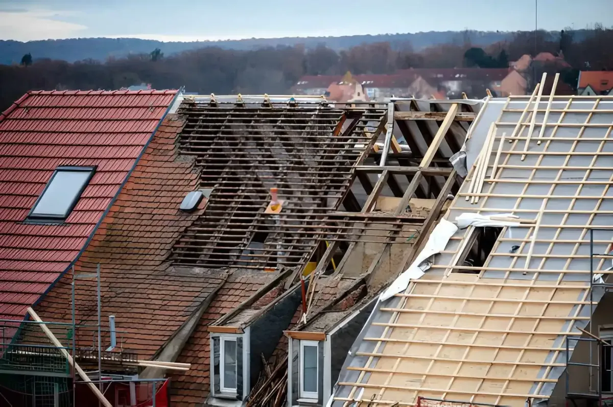 Residential roof mid-replacement with old shingles torn off and wood decking exposed near a skylight