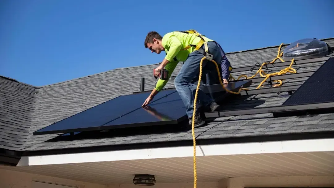 Technician installing solar panels on a residential shingle roof.