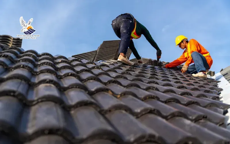 Roofing crew installing new tile roofing on a residential building.