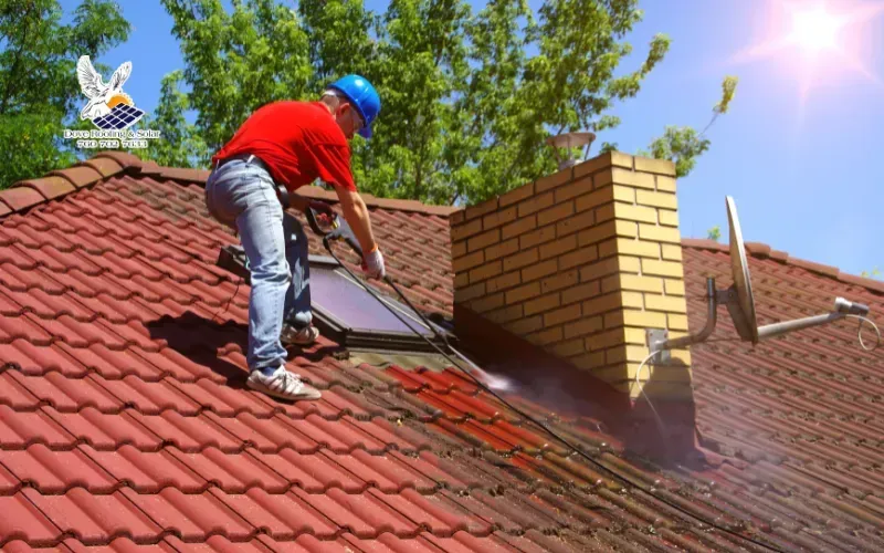 Roofing technician cleaning a clay tile roof near a chimney in Hidden River, CA