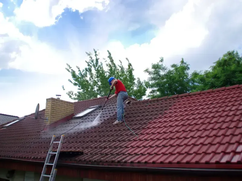 Roofer pressure washing a tile roof.