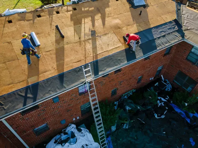 Aerial view of a roofing crew installing new asphalt shingles during a roof replacement