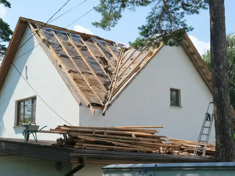 House roof under reconstruction with exposed rafters and underlayment