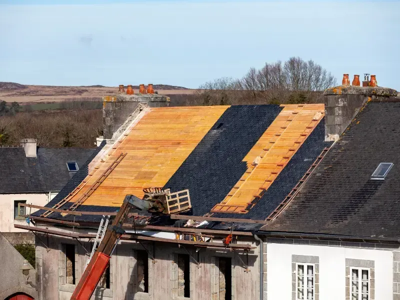 Roof under reconstruction showing slate tile sections and bare decking
