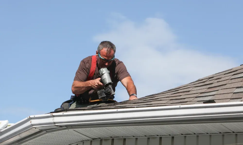 Hand lifting damaged shingle revealing gap at eave — what are signs of roof damage after a storm