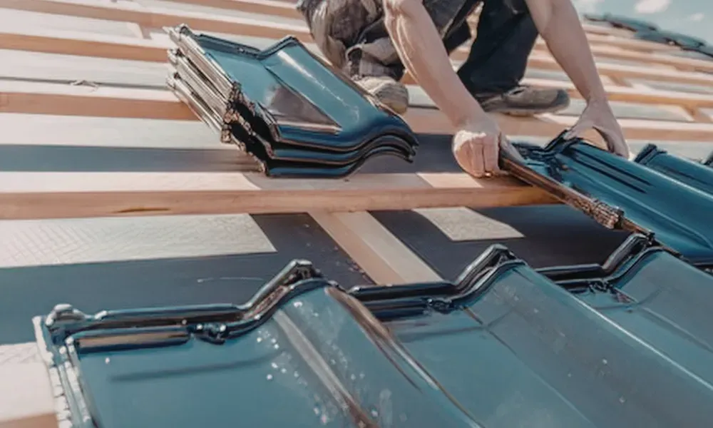 Gloved hand operating nail gun fastening brown asphalt shingles — how do you install roof shingles