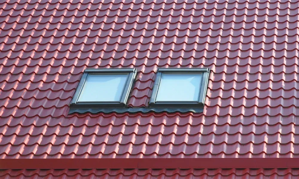 Black vented skylight on terracotta tile roof under blue sky — roofing services Palm Springs CA