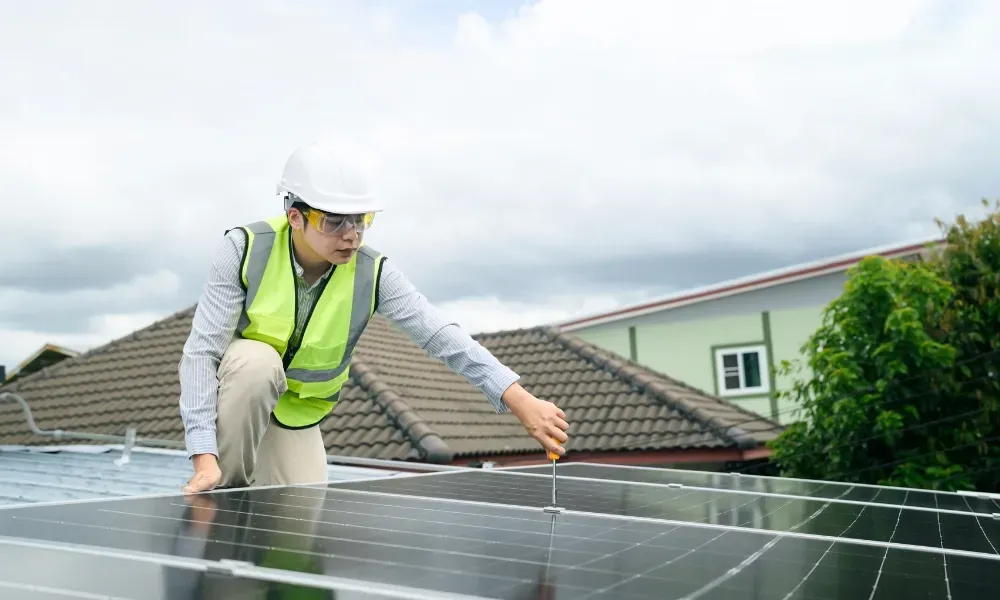Gloved hand operating nail gun fastening brown asphalt shingles — how do you install roof shingles