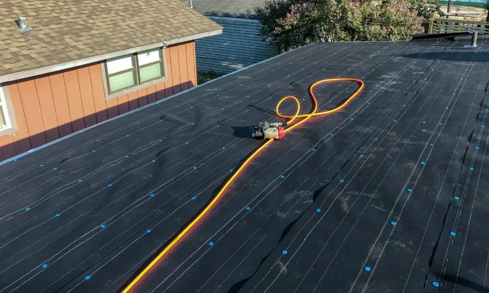 Gloved hand operating nail gun fastening brown asphalt shingles — how do you install roof shingles