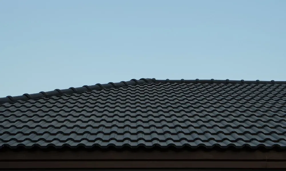 Close-up of pneumatic nail gun fastening new asphalt shingles — how do you install roof shingles