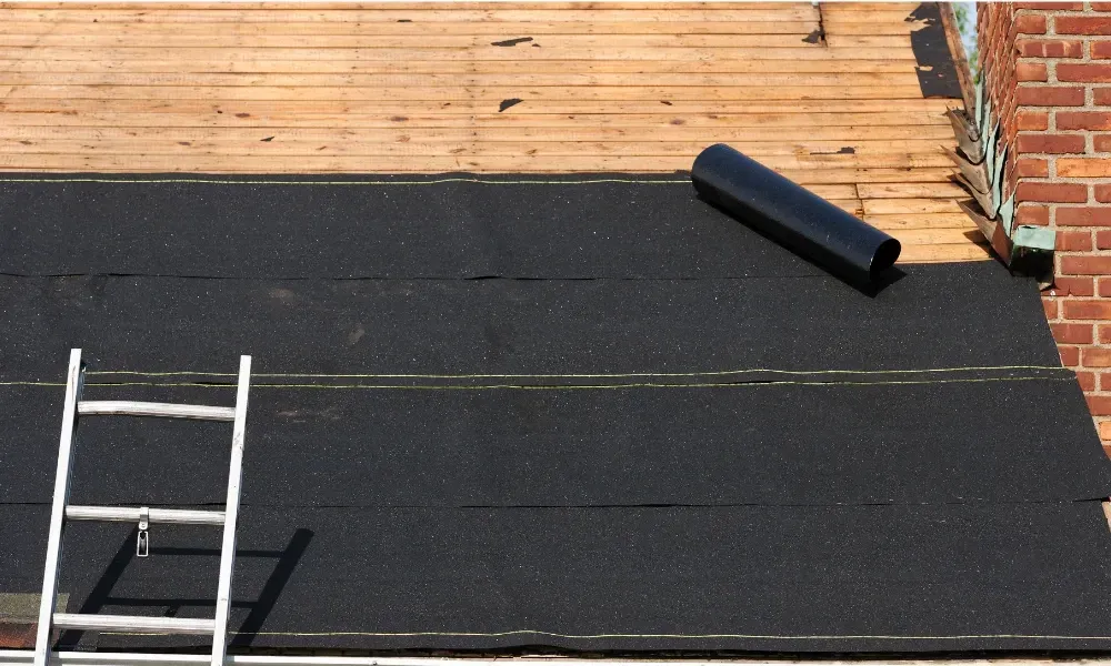 Gloved hand operating nail gun fastening brown asphalt shingles — how do you install roof shingles