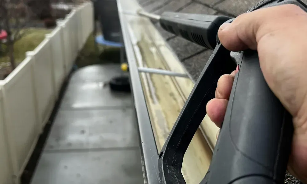 Worker power washing red clay tile roof to remove moss and debris — how to remove moss from roof