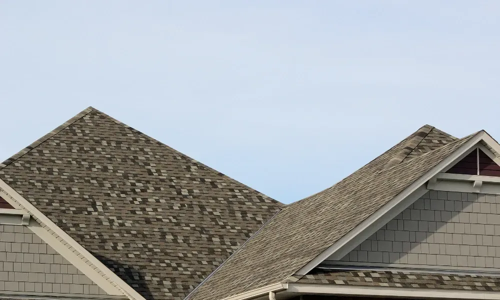 Close-up of pneumatic nail gun fastening new asphalt shingles — how do you install roof shingles